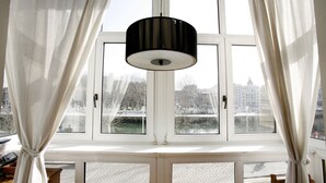 Quarto com uma grande janela, cortinas e luminária pendente.