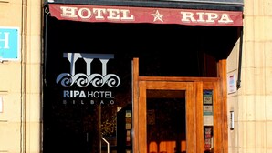 Entrada de hotel com uma placa indicando "HOTEL RIPA" e uma porta de madeira.
