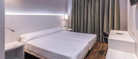 Una habitación de hotel moderna con una cama grande, mesitas de noche, un escritorio y una silla.