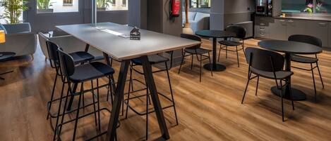 Un espacio de oficina moderno con una amplia mesa de reuniones, varias sillas y una zona de kitchenette.