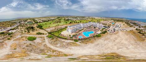 A resort with multiple buildings, a large pool, and a golf course.