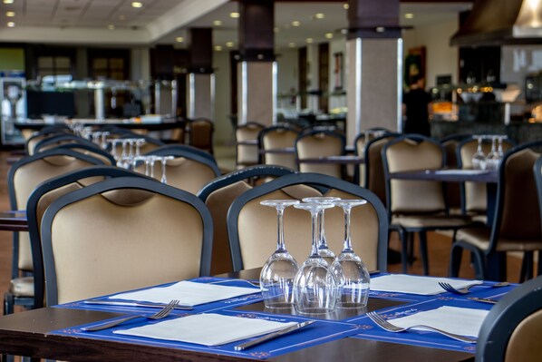 A restaurant with multiple tables set for dining, each with a set of cutlery and wine glasses.