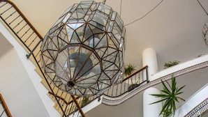 A multi-level interior with a spiral staircase, geometric ceiling light, and potted plants. - Ohtels Cabogata (Almeria)