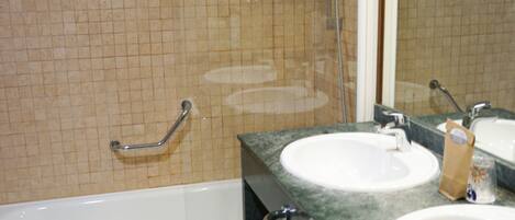 A bathroom with two sinks, a bathtub, and a shower.