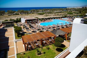 A resort with a large pool, outdoor seating, and a view of the ocean.