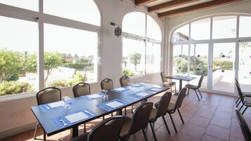 Un salón de conferencias con una larga mesa, sillas y ventanas amplias que dan a vistas del exterior.