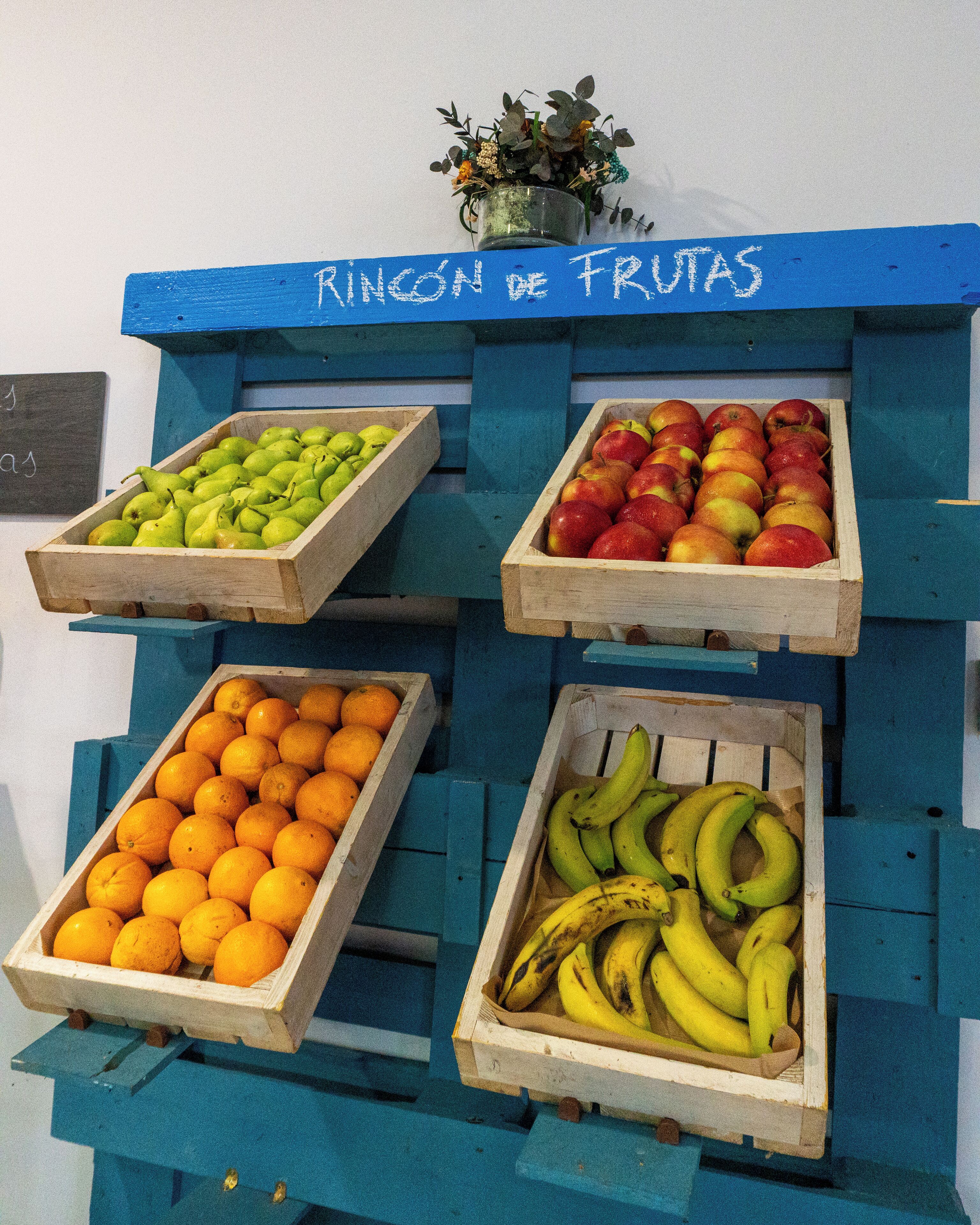 Een presentatie van fruit met houten kisten vol peren, appels, sinaasappels en bananen.