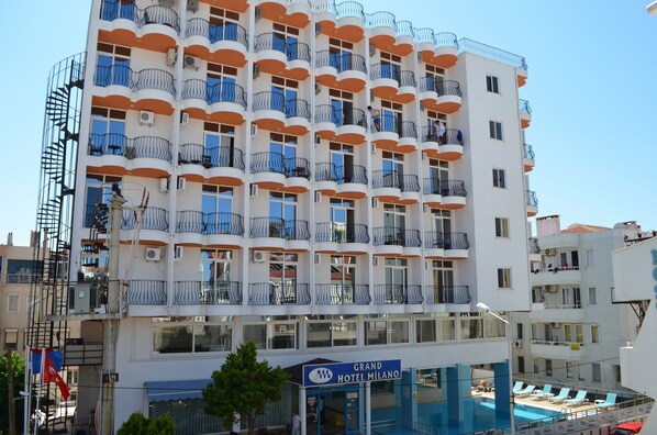 A multi-story hotel with balconies, a swimming pool, and a sign indicating it is the Grand Hotel Milano. - Grand Milano Hotel (Ayvalik)