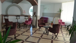 A lobby with check-in counters, seating areas, and potted plants. - Grand Milano Hotel (Ayvalik)