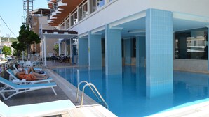 A swimming pool area with lounge chairs and a covered seating area. - Grand Milano Hotel (Ayvalik)
