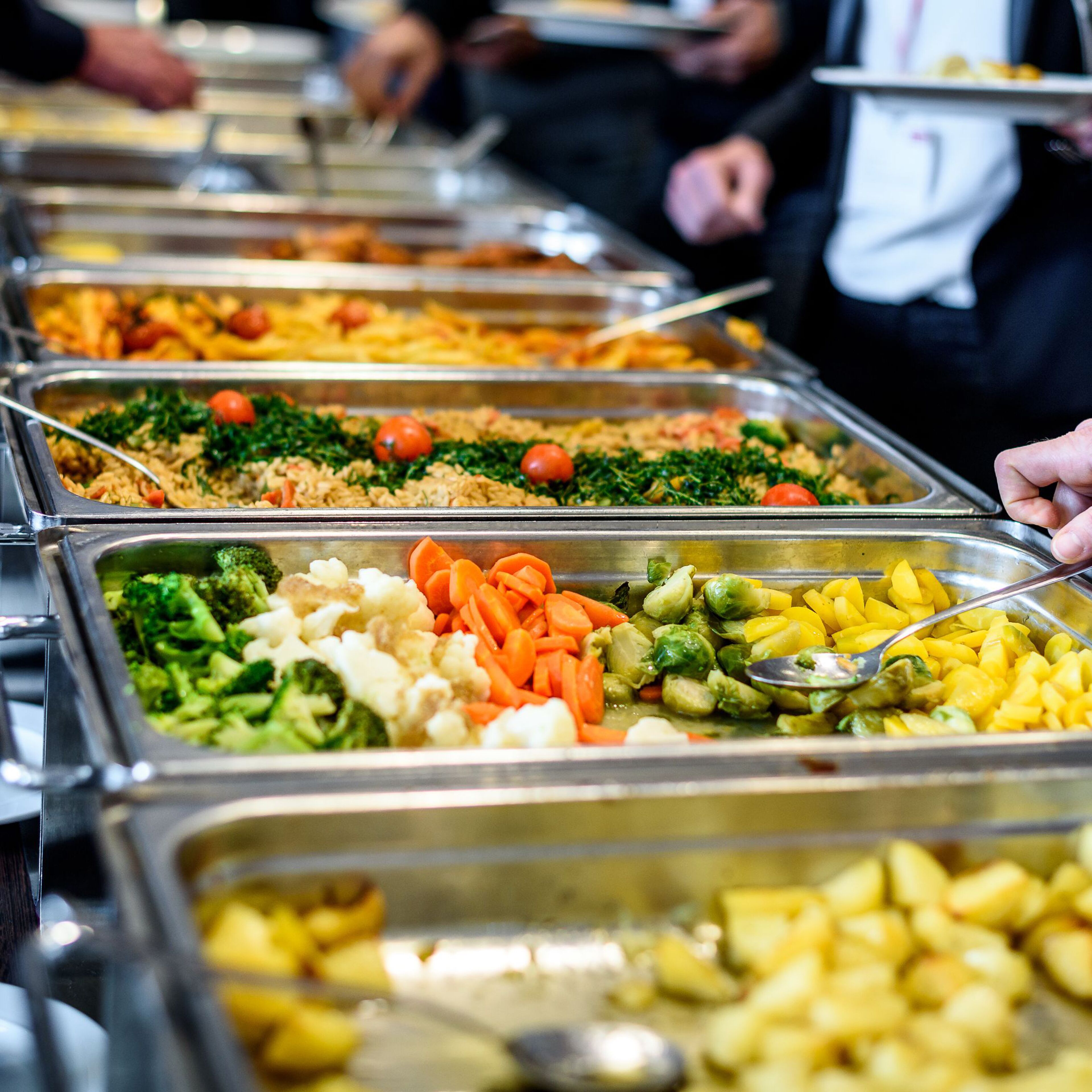 A buffet with various food options including rice, vegetables, and fruits.