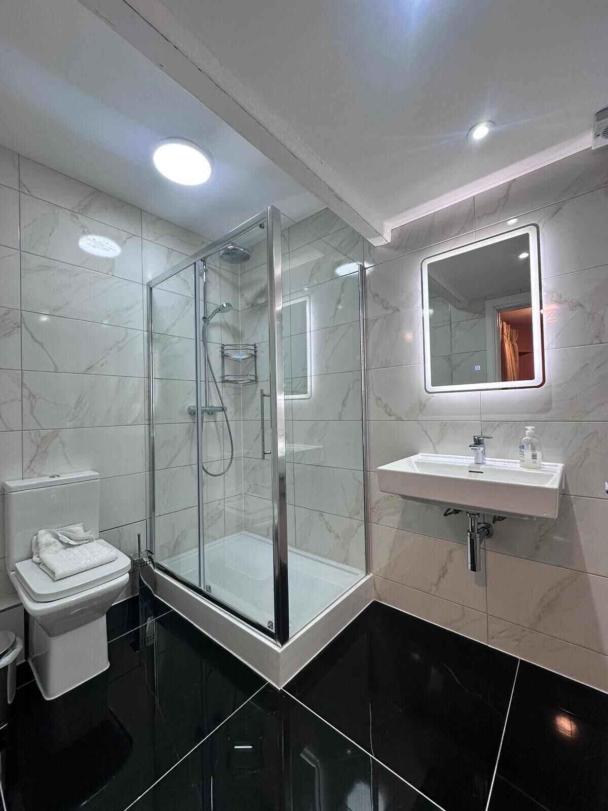 Ein modernes Badezimmer mit einer Glaskabine zur Dusche, einem weißen Waschbecken und einem Spiegel.