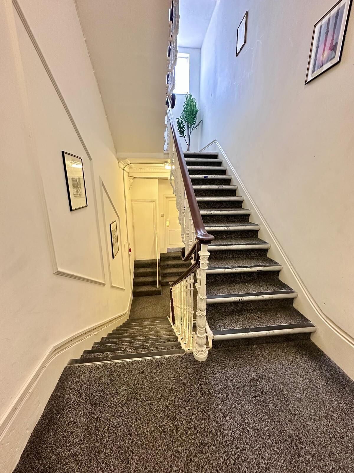 A staircase with a handrail, carpeted steps, and a door at the top.
