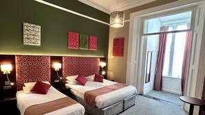 A hotel room with two beds, a chandelier, and a large window with curtains. - Acacia Hotel (London)