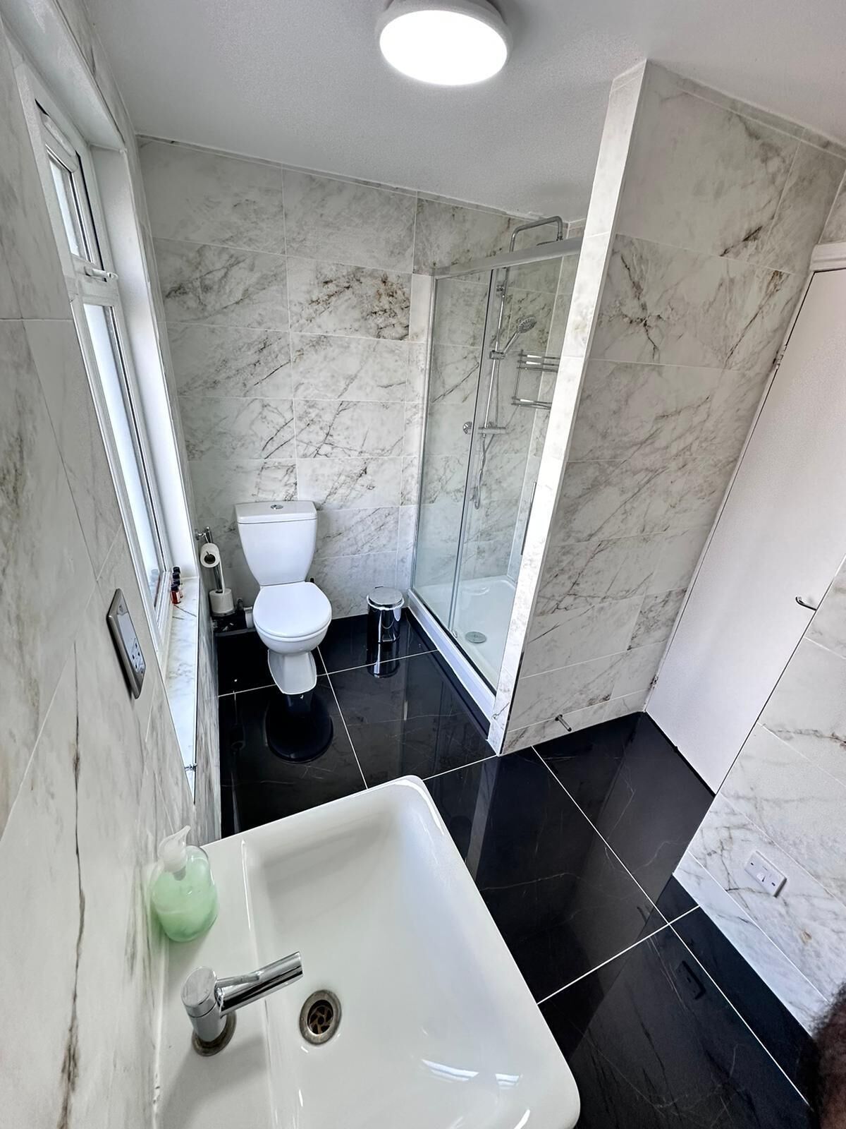 A bathroom with a white toilet, a shower with glass doors, and a sink with a mirror.