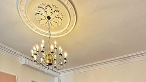 A spacious dining area with a chandelier, patterned carpet, and a mix of red and brown upholstered chairs. - Acacia Hotel (London)