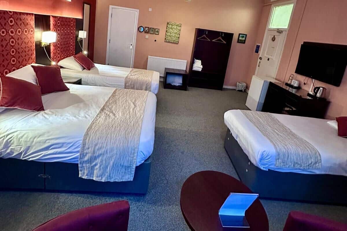 A hotel room with two beds, a small table, and a TV.
