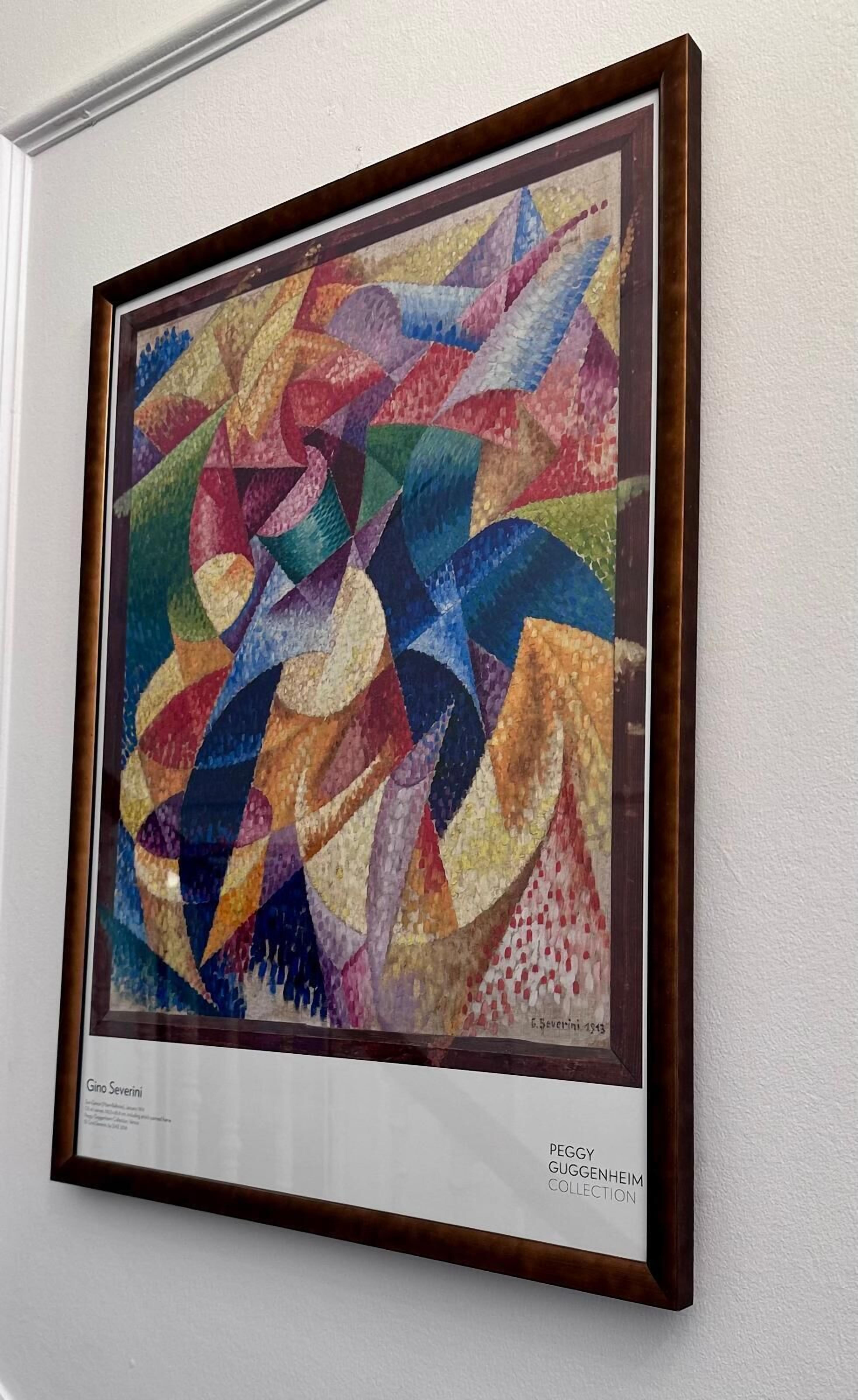 Un cuadro abstracto enmarcados con un patrón geométrico, colgado en una pared blanca.