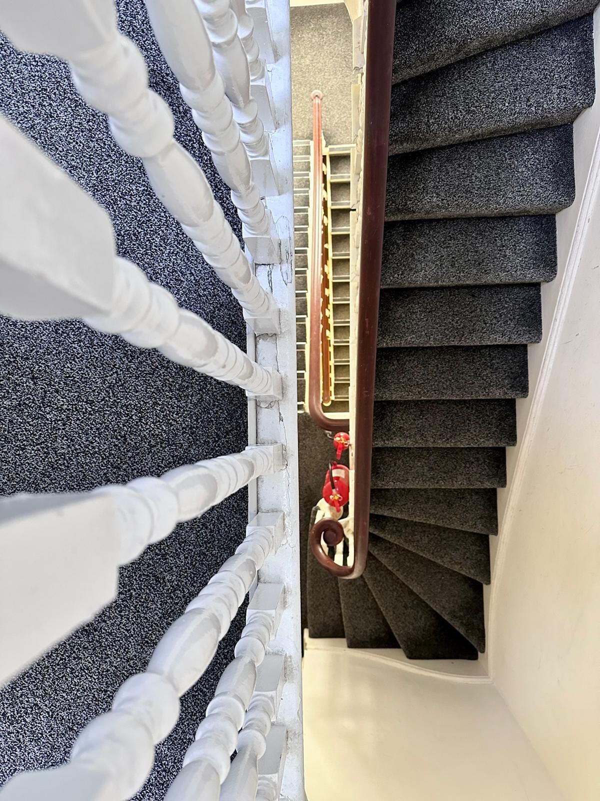 A spiral staircase with white balustrades and dark carpeted steps.