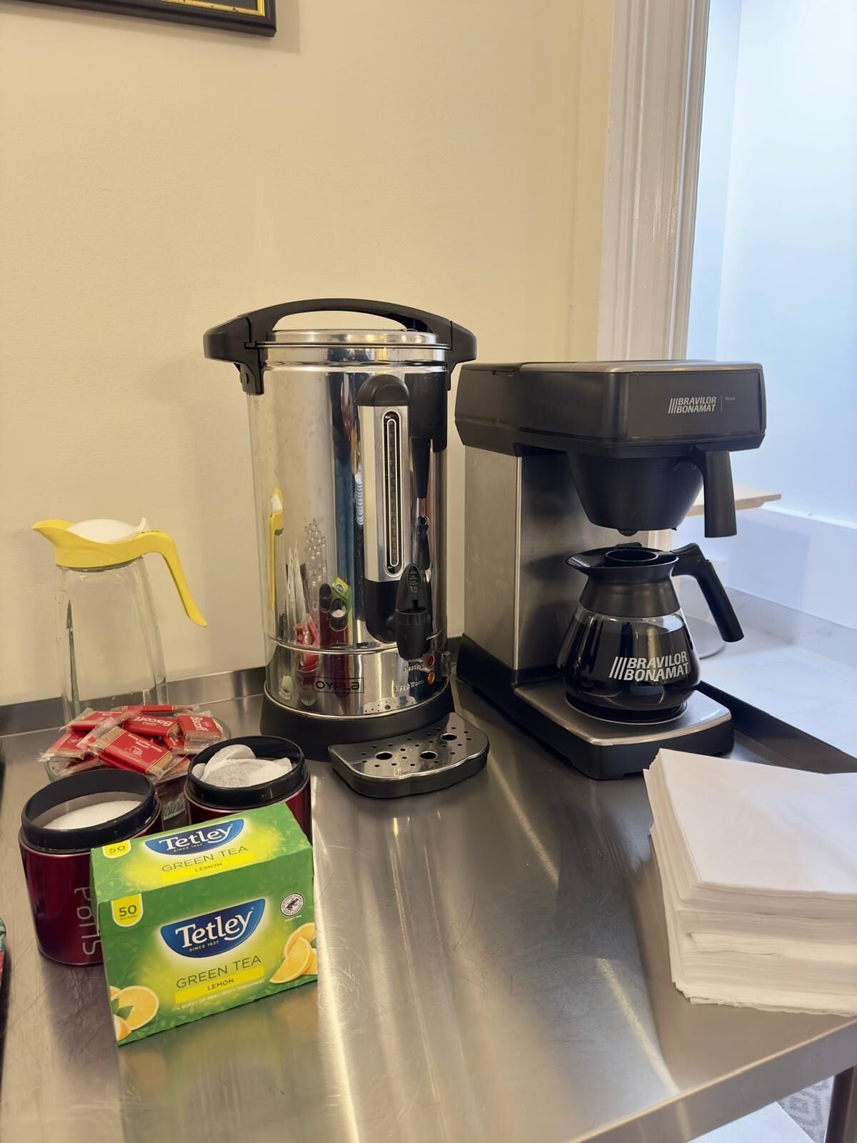Un taulell de cuina amb una cafetera, un batlle i caixes de te verd Tetley.