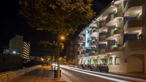 A modern hotel with multiple balconies, a well-lit street, and parked cars. - Jaime I Hotel Peñiscola (Peniscola)