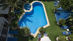 An aerial view of a swimming pool surrounded by palm trees and blue lounge chairs. - Jaime I Hotel Peñiscola (Peniscola)