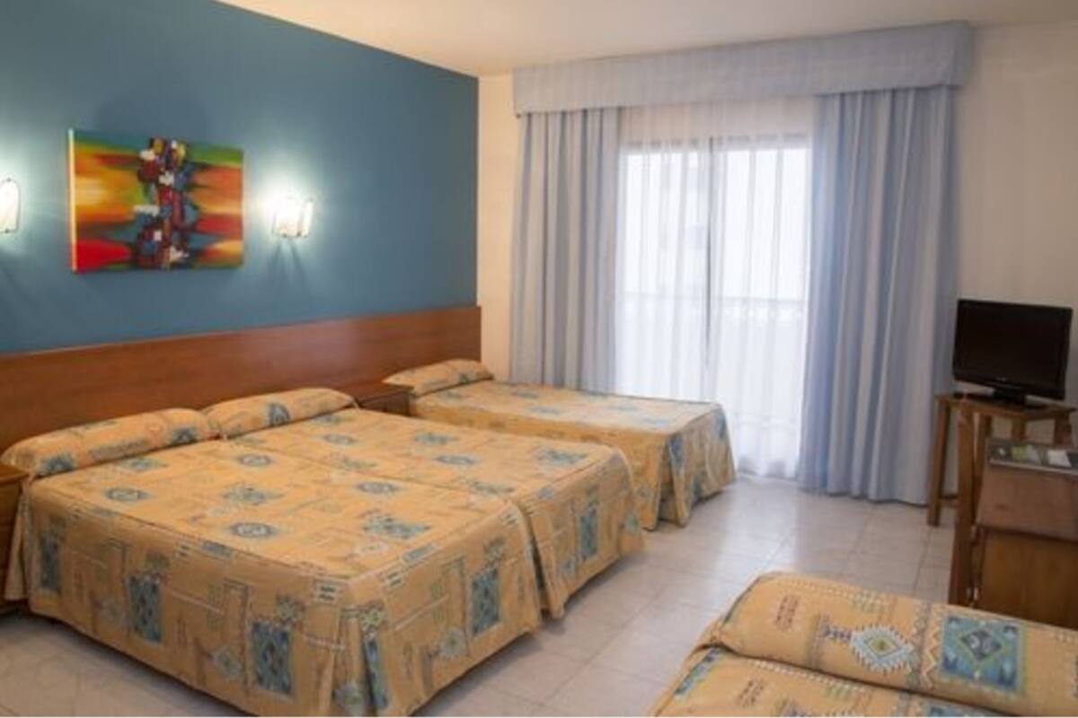 Una habitación de hotel con dos camas, televisión y un cuadro en la pared.
