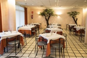 A restaurant with tables set for dining, featuring a tiled floor and a tree mural on the wall.