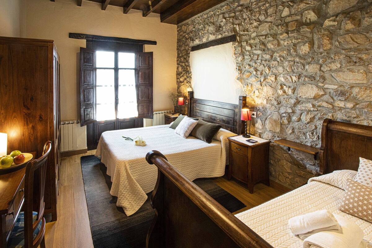 Un dormitorio con pared de piedra, muebles de madera y una cama con colcha.