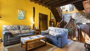 Una sala de estar acogedora con dos sofás, una mesa de centro y una escalera que sube a un nivel superior.