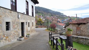 Una estrecha calle empedrada con edificios tradicionales, una cerca de madera y un banco.