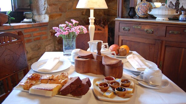 Una mesa con bollos, mermeladas y un juego de té para el desayuno.
