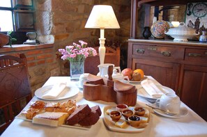 A breakfast setting with pastries, jams, and a tea set on a table.