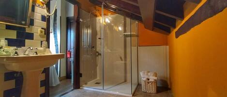 Un baño con cabina de ducha de vidrio, lavamanos y salpicadero de azulejos.