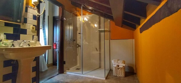 A bathroom with a glass shower enclosure, a sink, and a tiled backsplash.