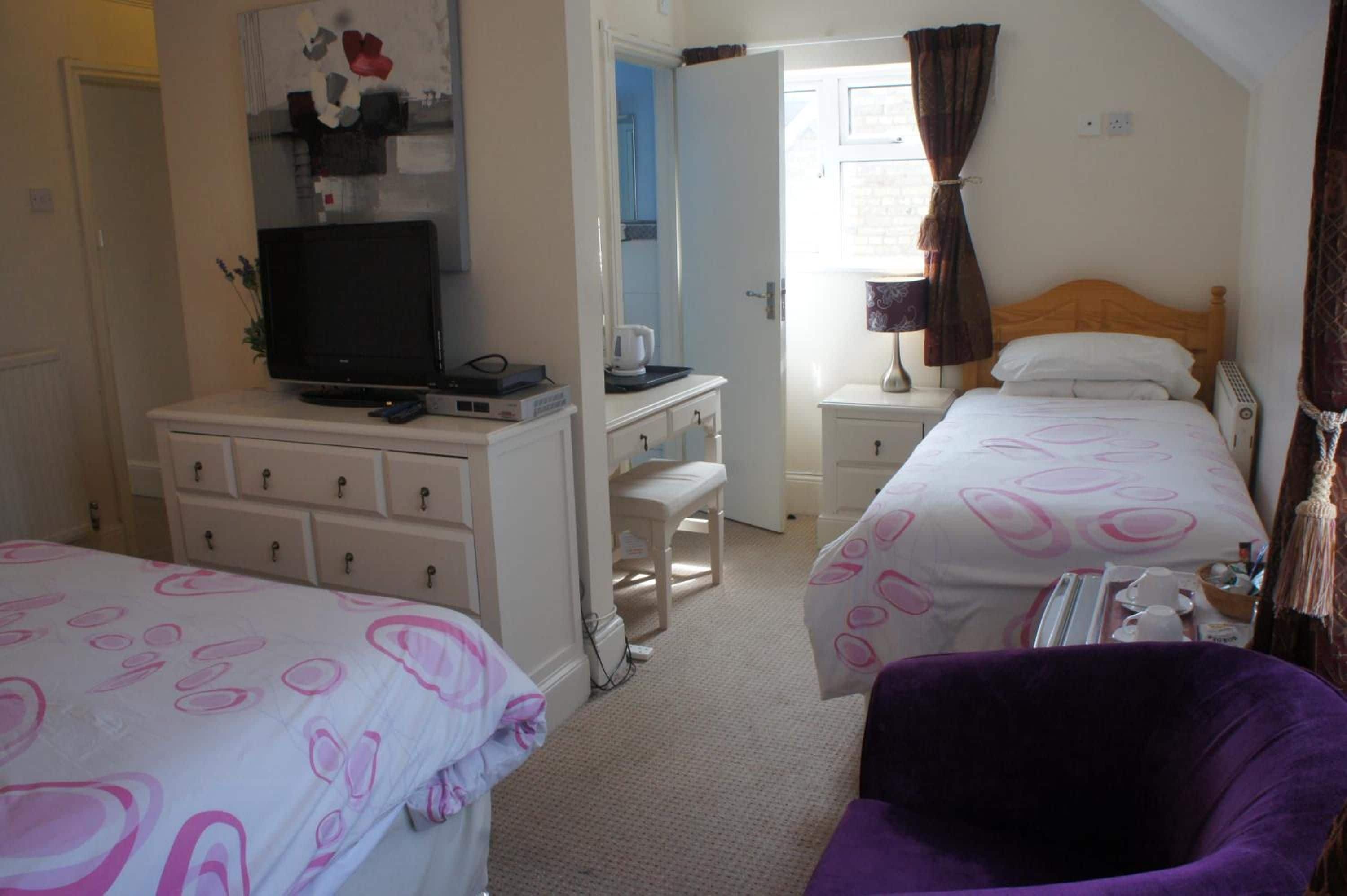 A hotel room with two beds, a desk with a computer, a television, and a chair.