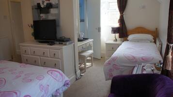 A hotel room with two beds, a desk with a computer, a television, and a chair.