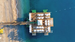 An aerial view of a beachside restaurant with outdoor seating and a wooden deck. - Club Hotel Phaselis Rose - All Inclusive (Kemer)