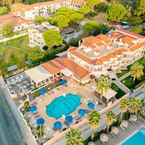 A hotel with a swimming pool, outdoor seating, and a landscaped garden. - Panorama (Skiathos)