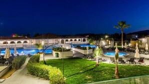 A hotel pool area with multiple pools, lounge chairs, and umbrellas. - Exotica Hotel (Zakynthos)