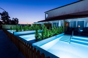 Area piscina esterna moderna con un solarium in legno e una ringhiera in vetro.