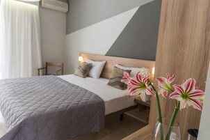 Una camera da letto con un letto, cuscini, un comodino con un vaso di fiori e una testiera in legno.