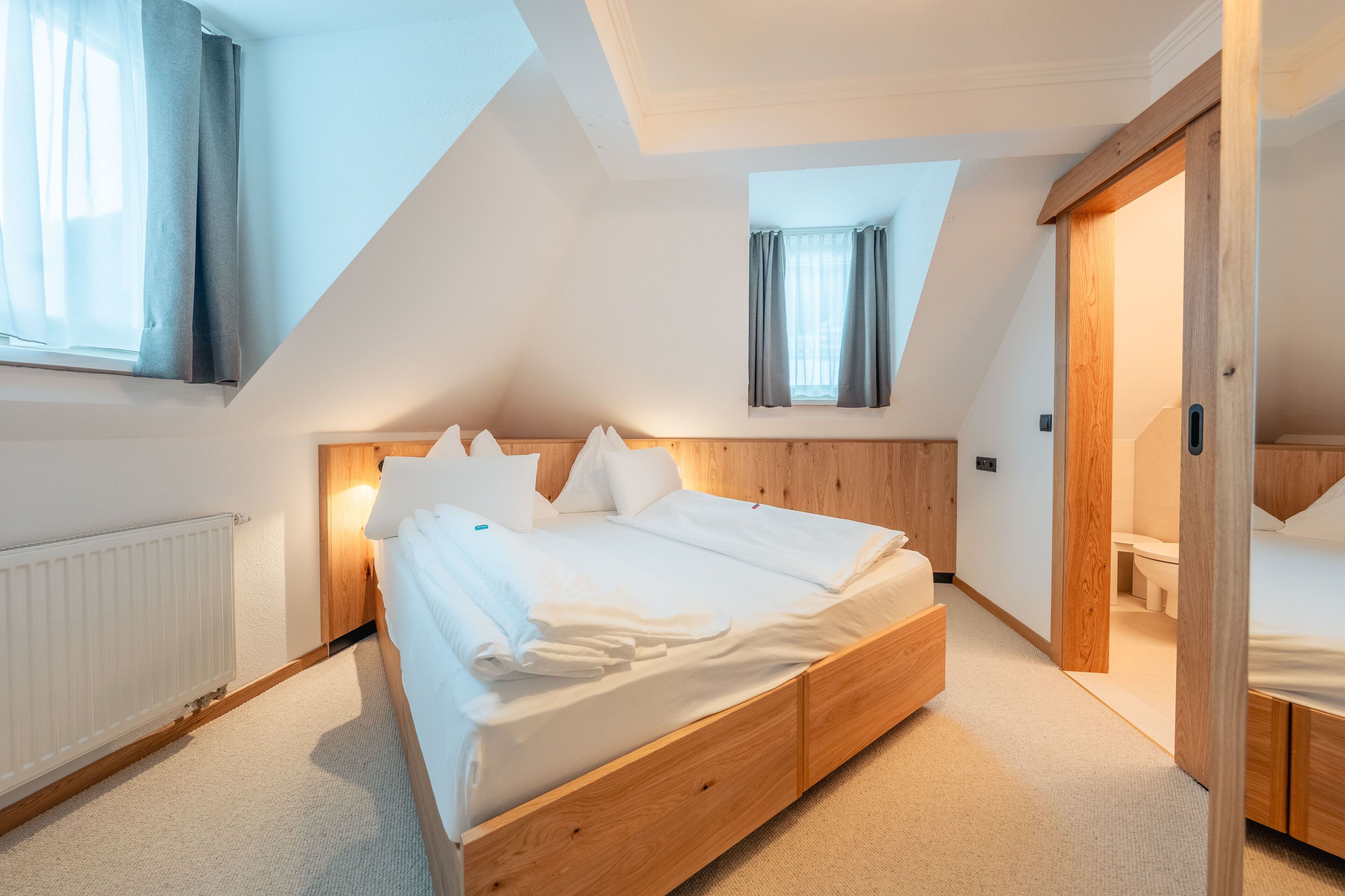 A bedroom with a wooden bed, a radiator, and a skylight.