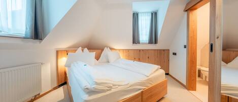 A bedroom with a wooden bed, a radiator, and a skylight.