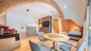 A modern loft-style room with a dining area, a built-in kitchen, and a cozy seating area. - Hotel Ischgl (Ischgl)