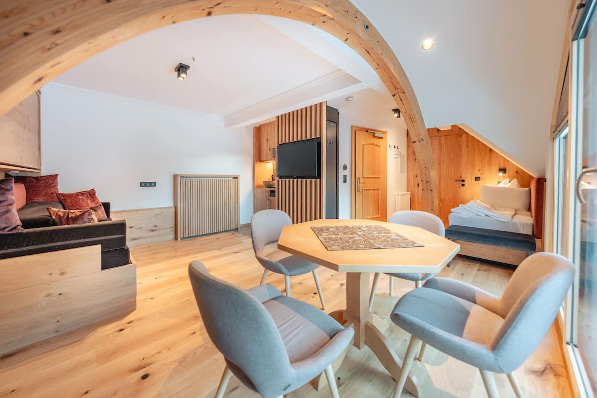 A modern loft-style room with a dining area, a built-in kitchen, and a cozy seating area.