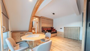 A modern interior with a wooden ceiling, a dining table with chairs, a sofa, and a radiator. - Hotel Ischgl (Ischgl)