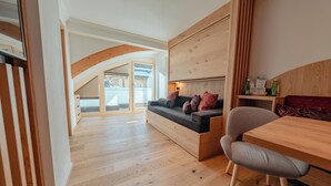 A modern interior with a wooden floor, a sofa with cushions, a wooden table, and a chair. - Hotel Ischgl (Ischgl)