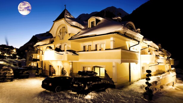 A snow-covered building with a moon in the sky, featuring a prominent tower and multiple windows. - Hotel Ischgl (Ischgl)
