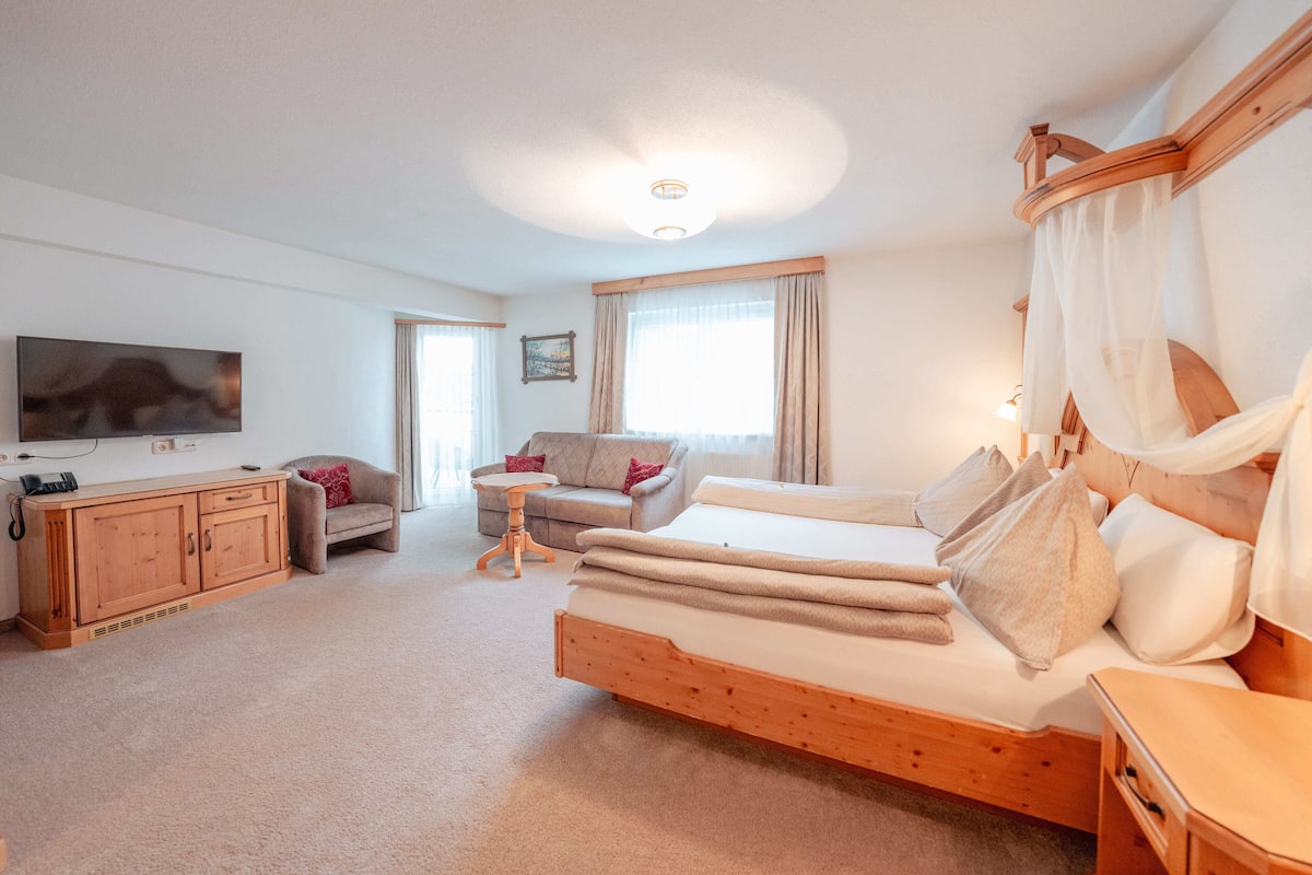 A bedroom with a wooden bed, a sofa, a TV, and a wooden cabinet.